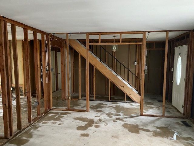 Interior framing exposed after asbestos drywall removal with staircase visible