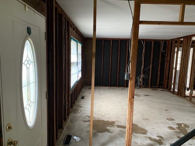 Open floor plan after asbestos drywall removal showing front entry and studs